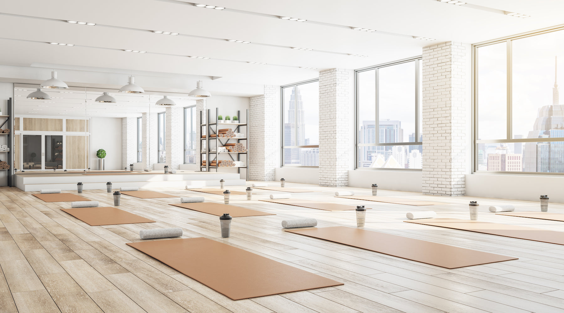 A spacious room with yoga mats, cups, towels, and plants.