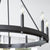 A black chandelier with lights, featuring a wagon wheel design. This farmhouse-inspired fixture combines industrial aesthetics with a beautiful finish. Customize the look with candle sleeves in aged brass, noir, or satin nickel. Elevate your space with the Aura wagon wheel chandelier from Quorum International.