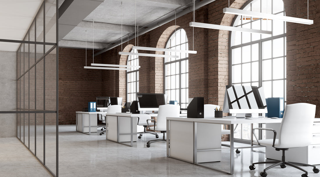Commercial lighting installed above desks in brick office with arch windows