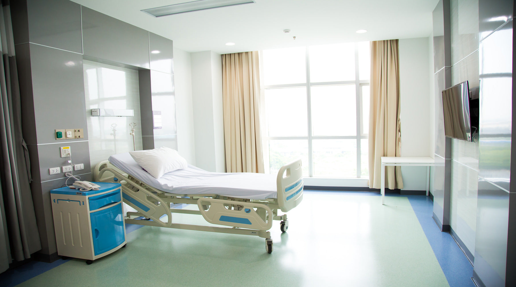 Hospital recovery room with beds illuminated by recessed ceiling lights