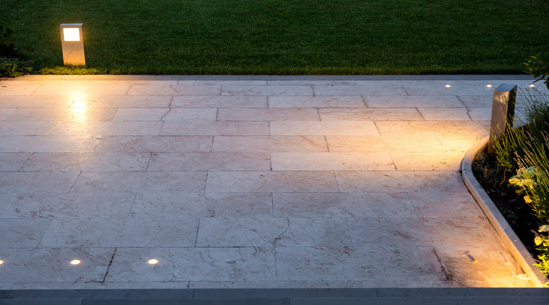 Landscape lighting shown illuminating pavement of marble tiles and a stone border area