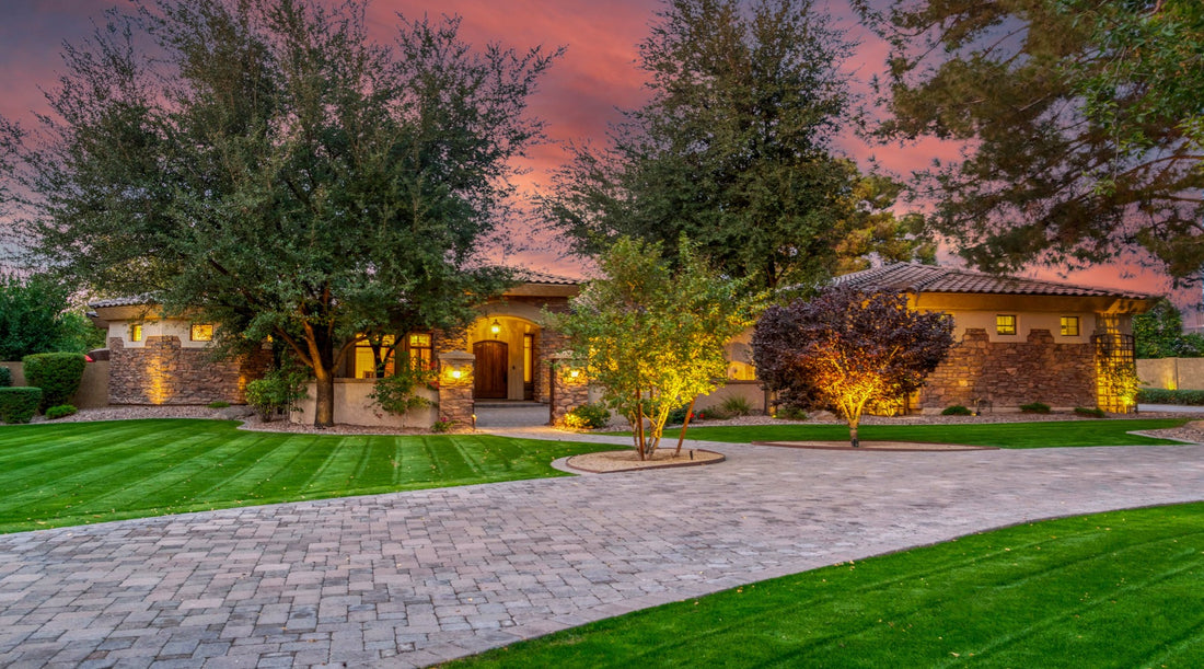 Landscape lighting shown illuminating the trees of luxury home at sunset