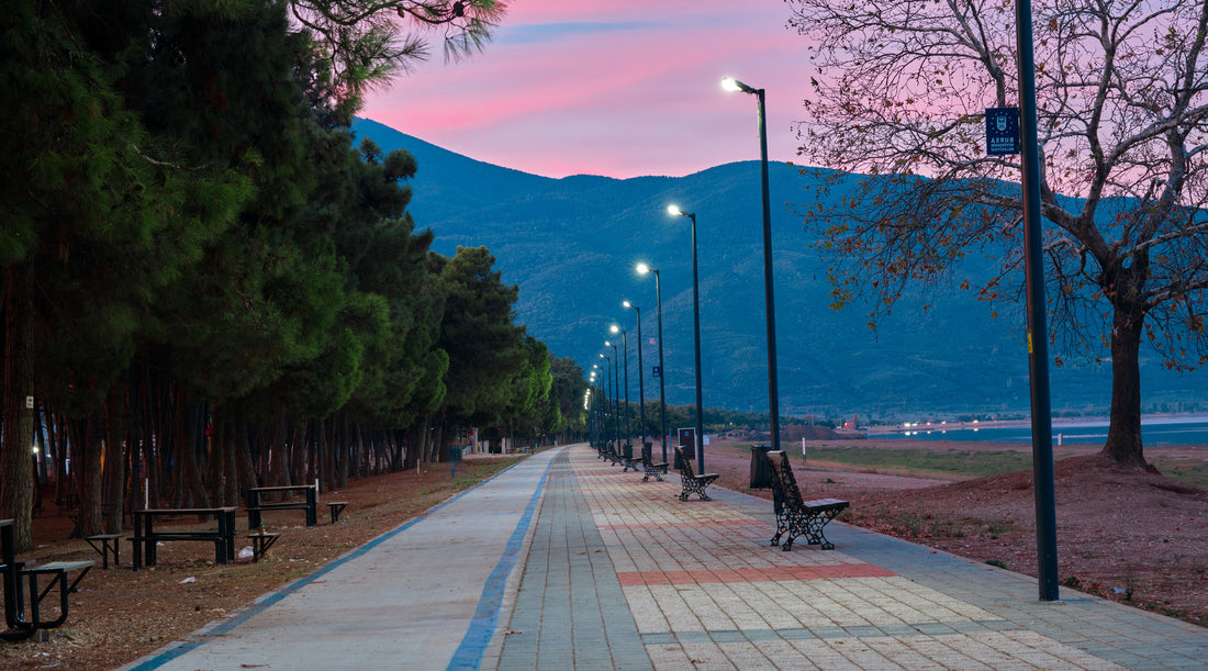 LED retrofit bulbs used in street lamps post along cobblestone way located in public park with mountain and red sky