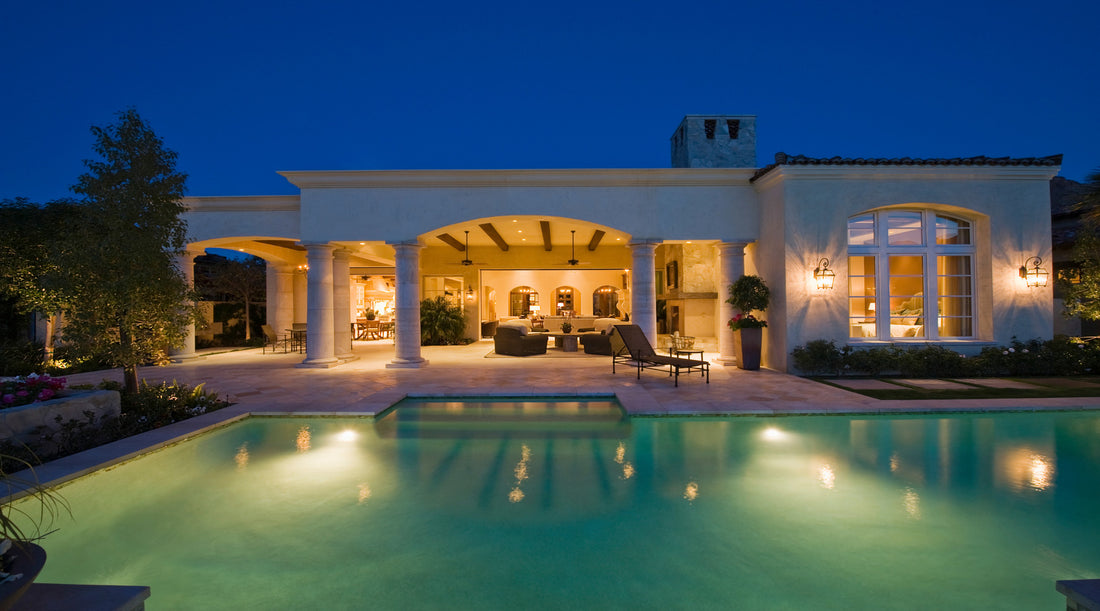 Outdoor lighting illuminating the swimming pool and exterior of home at night