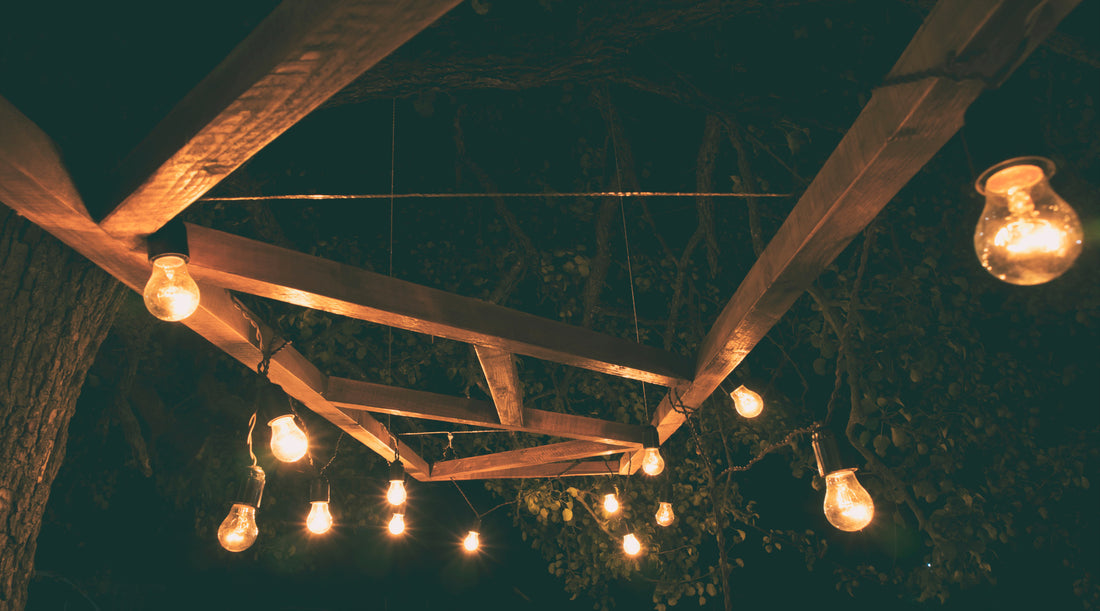 Outdoor string lights hanging from wooden planks above patio