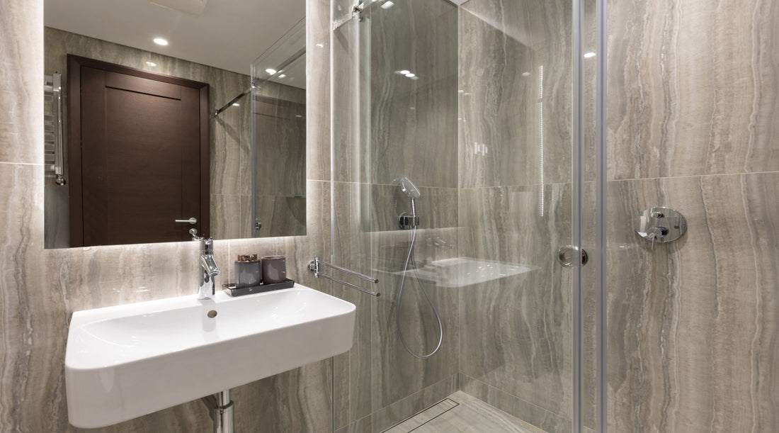 Recessed lighting installed in luxury bathroom with marble walls above glass shower cabin