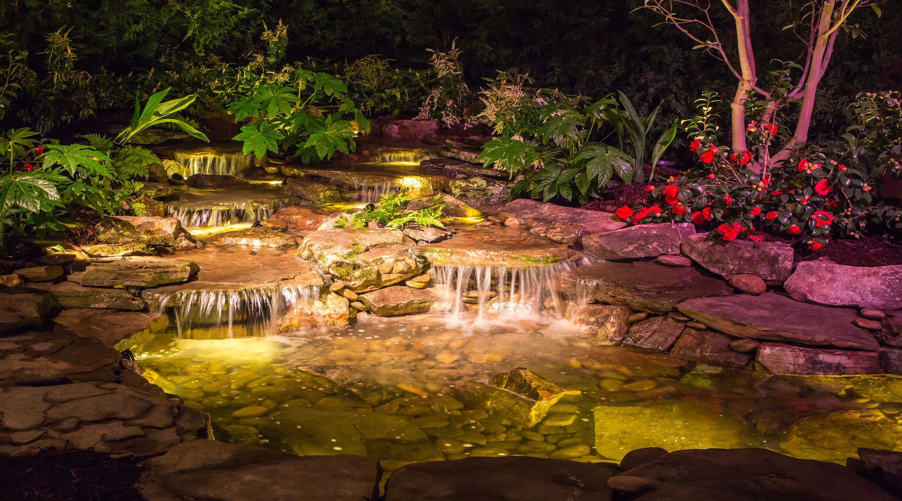 Pond lighting installed to illuminate the beautiful waterfall of a pond at night