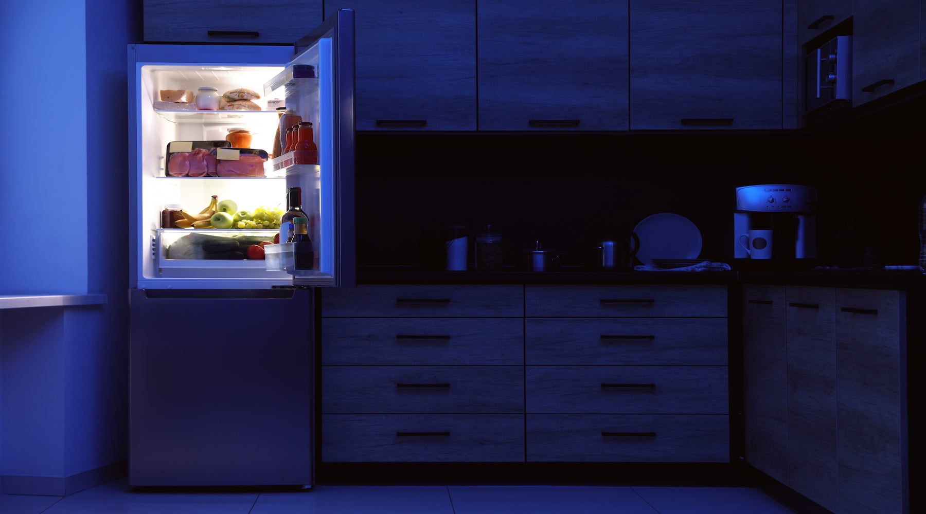 Refrigerator with light bulb on in a dark kitchen