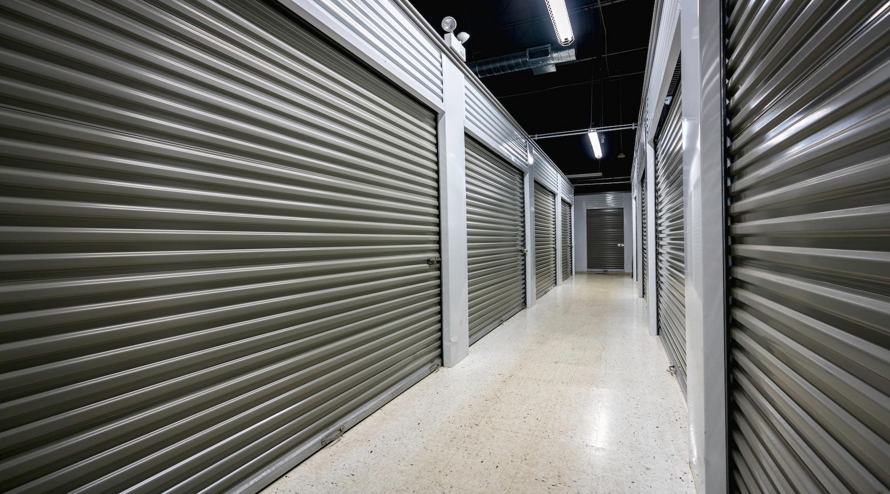 Storage unit lighting installed in large storage facility corridor with garage doors