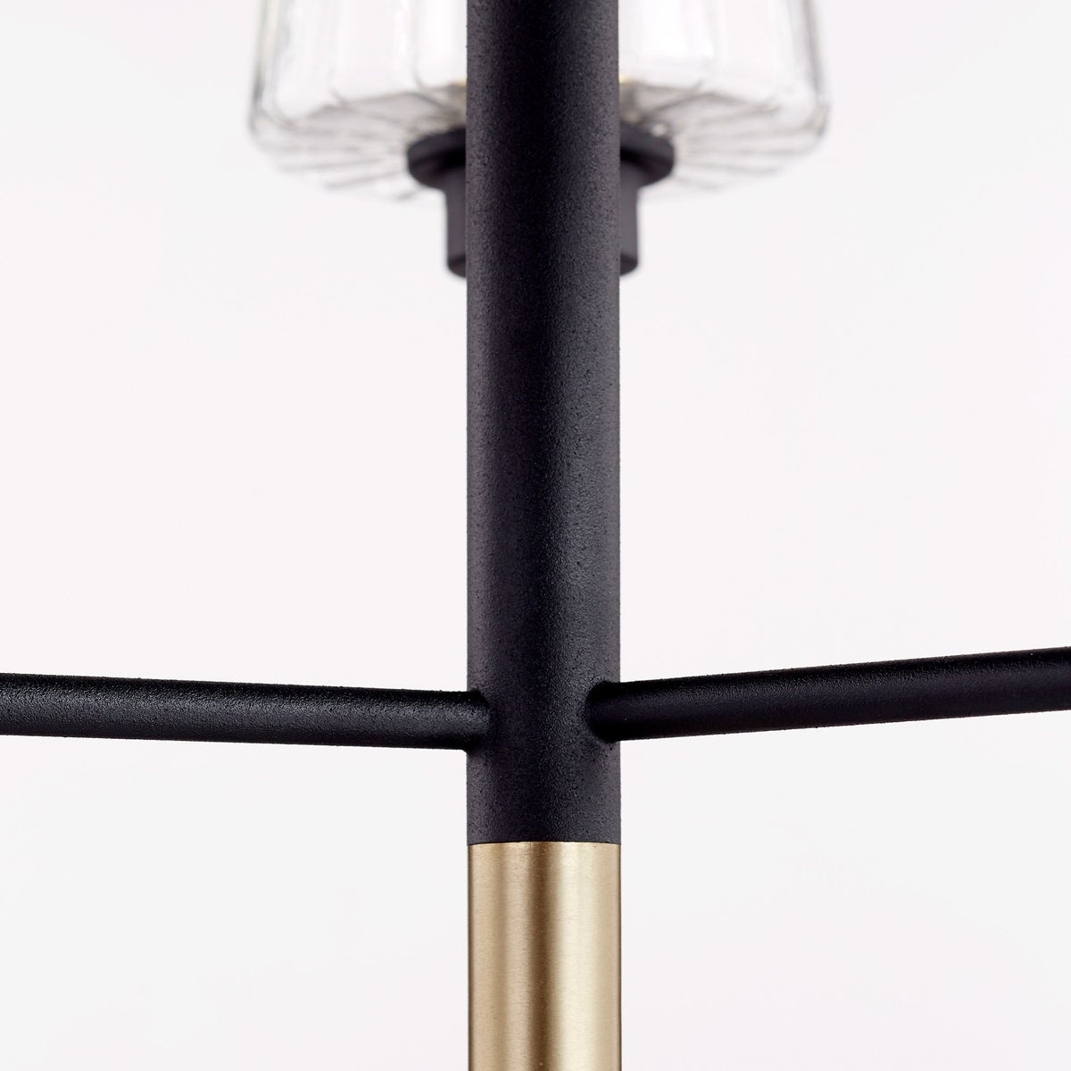 Bathroom chandelier with three clear glass shades, tulip-shaped and fluted. Minimalist-inspired design with aged brass and noir finish. Suitable for bathrooms, outdoor kitchens, and covered patios. Adjustable chain/stem hung suspension system.