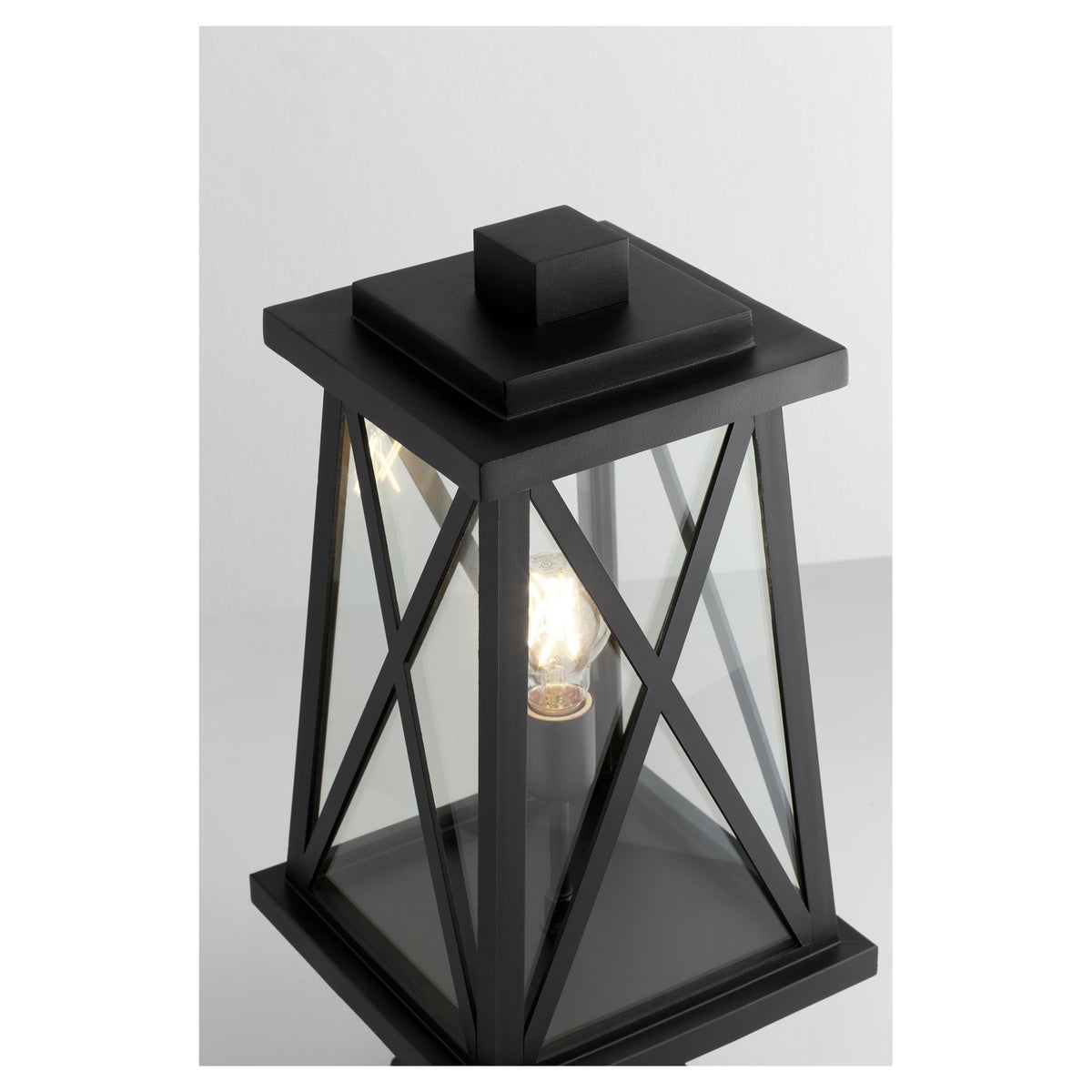 A black outdoor post light with a classic X-brace design, emitting a warm glow. Perfect for any outdoor space. Brand: Quorum International. Wattage: 100W. Input Voltage: 120V. Bulbs: 1 (not included). Bulb Base Type: Medium E26. Dimmable: Yes. Certifications: UL Listed. Safety Rating: Wet Location. Finish: Noir. Dimensions: 9.25"W x 18.5"H. Warranty: 2 Years.