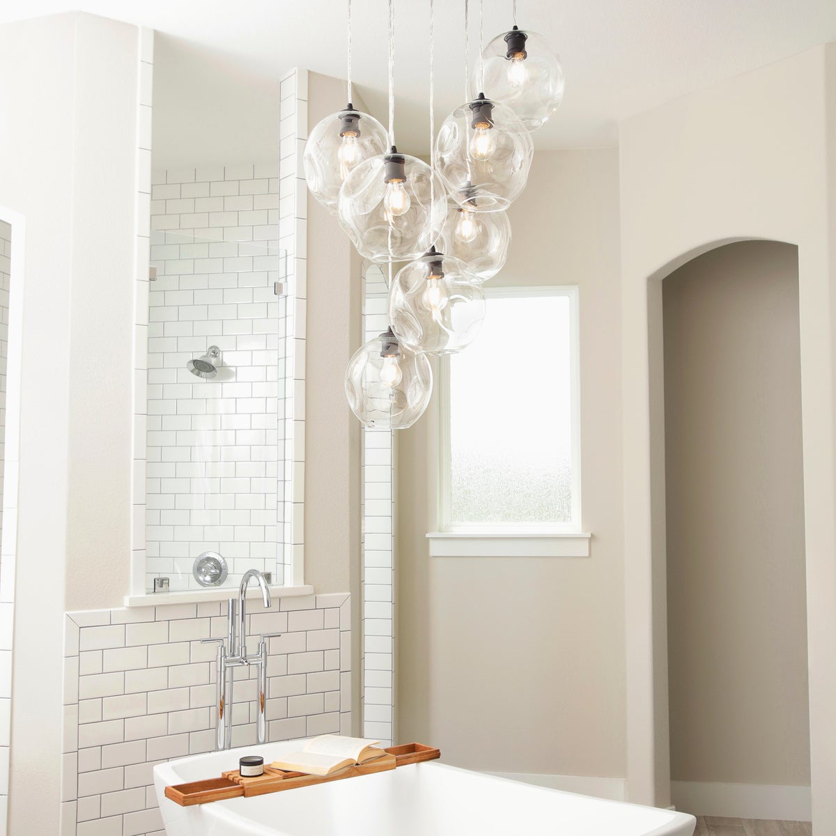 Cluster Pendant Light in a contemporary bathroom with a bathtub, chandelier, and clear glass lights from the ceiling.