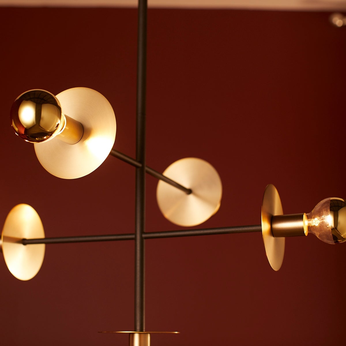 Contemporary pendant light with gold circles and light bulbs, providing multi-directional radiance. Two-toned design in noir and aged brass finishes. Damp Listed for indoor/outdoor installation. 18.5"W x 24"H.