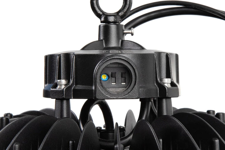 Tight side detail of the LED UFO high bay housing highlighting the open gasketed access port exposing CCT and wattage-select switches, ring bolt mounting point, finned heat sink, and dual black cable looms carrying black/green/white and purple/pink conductors; 100/125/150W, 15,000–22,500 lm, 4000K/5000K/5700K, 0–10V dimming, 120–277V.