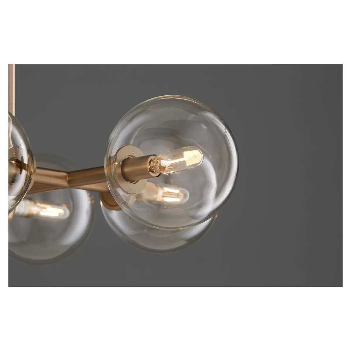 Linear Sputnik Chandelier with clear glass domes and aged brass frames, creating a mid-century modern appeal. 8 bulbs, 60W, dimmable. UL Listed, Damp Location. 18"W x 14"H x 37.5"L. 2-year warranty.