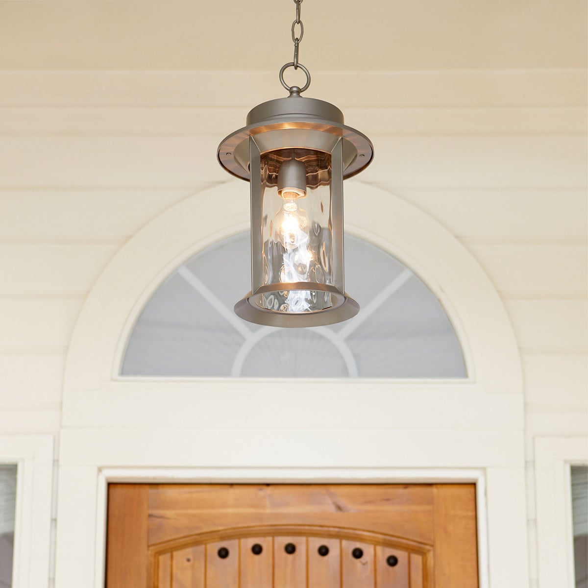 Mid Century Modern Outdoor Hanging Light with hammered glass panes, clean-lined drum silhouette, and durable metal construction. Casts bright light on your outdoor space.