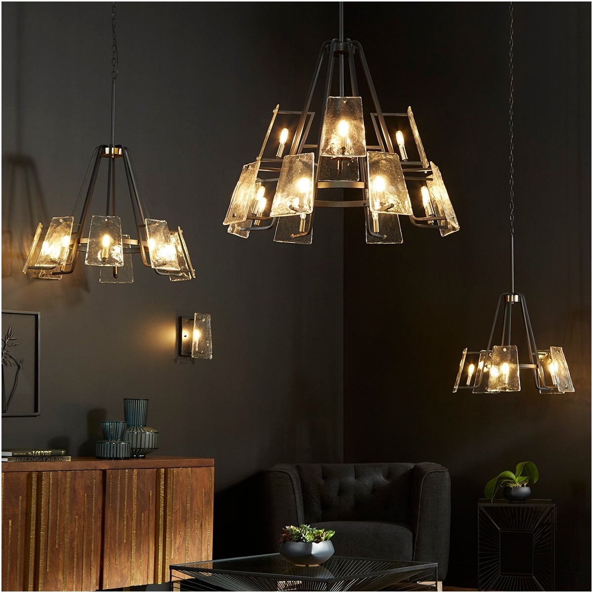 Outdoor chandelier with conical shape, linear framing, and frosted glass trapezoid shades. Mid-century modern design with aged brass-noir finish. Suspended from chain and stem mounting system. Suitable for covered outdoor spaces or washrooms. 36"W x 30"H.