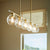 Transitional Linear Chandelier with clear glass bulbs, aged brass finish, and acrylic accents. 5-bulb fixture for indoor use.