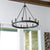 Wagon Wheel Chandelier hanging from the ceiling, combining farmhouse design with an industrial aesthetic. Features candle sleeves in aged brass, noir, and satin nickel finishes for customization. Elevate your space with this stunning fixture.