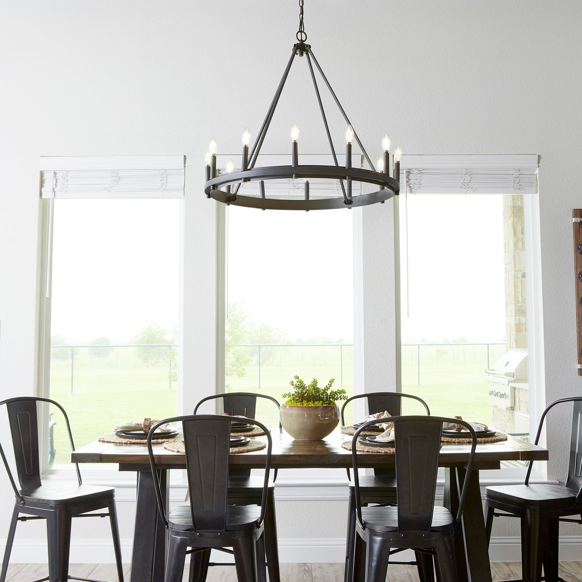A farmhouse-industrial wagon wheel chandelier with candle sleeves in aged brass, noir, and satin nickel finish options. Elevate your space with this superior fixture from Quorum International. 32"W x 28.25"H. 12 bulbs, 60W, dimmable. UL Listed for dry locations. 2-year warranty.