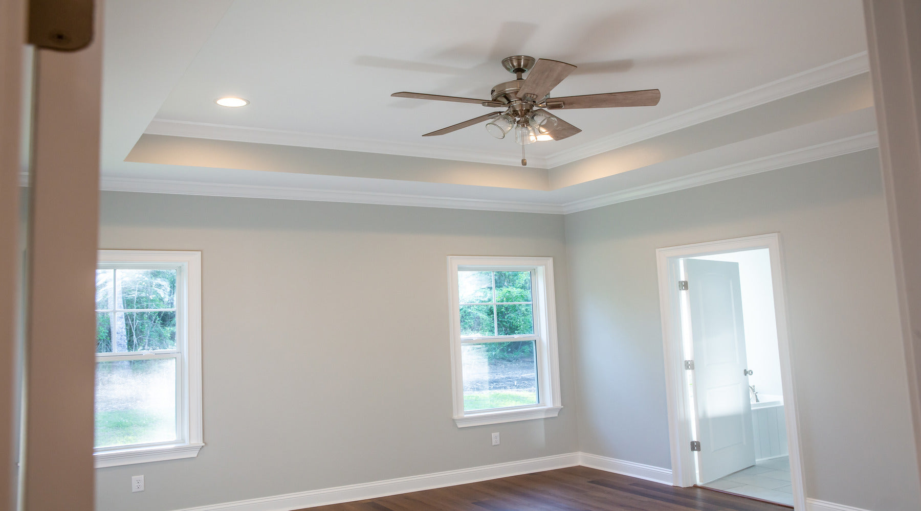 Ceiling fan shown in master bedroom with trey ceiling and hardwood floors