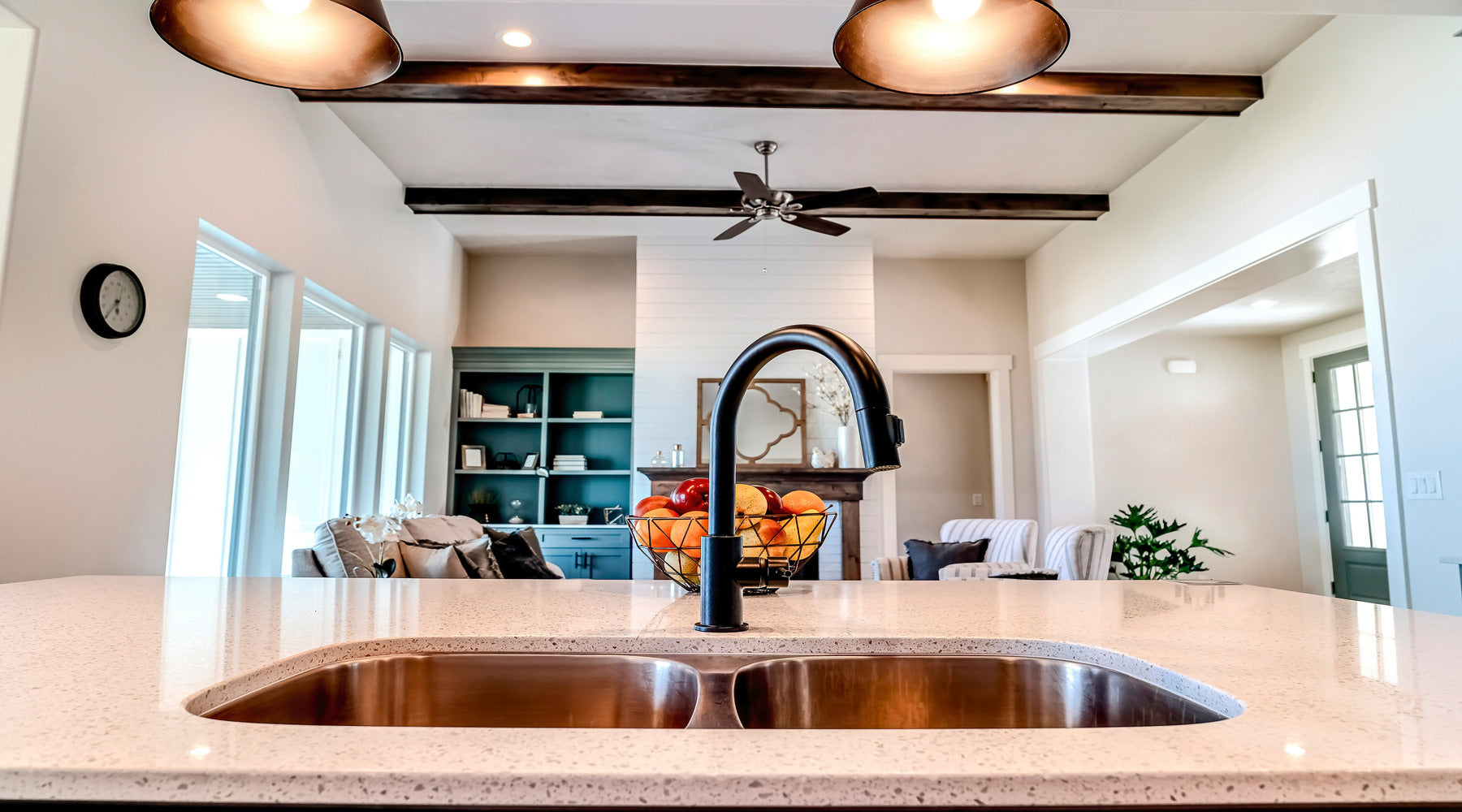 Close up view of kitchen island with ceiling fan shown in cozy living room in the background