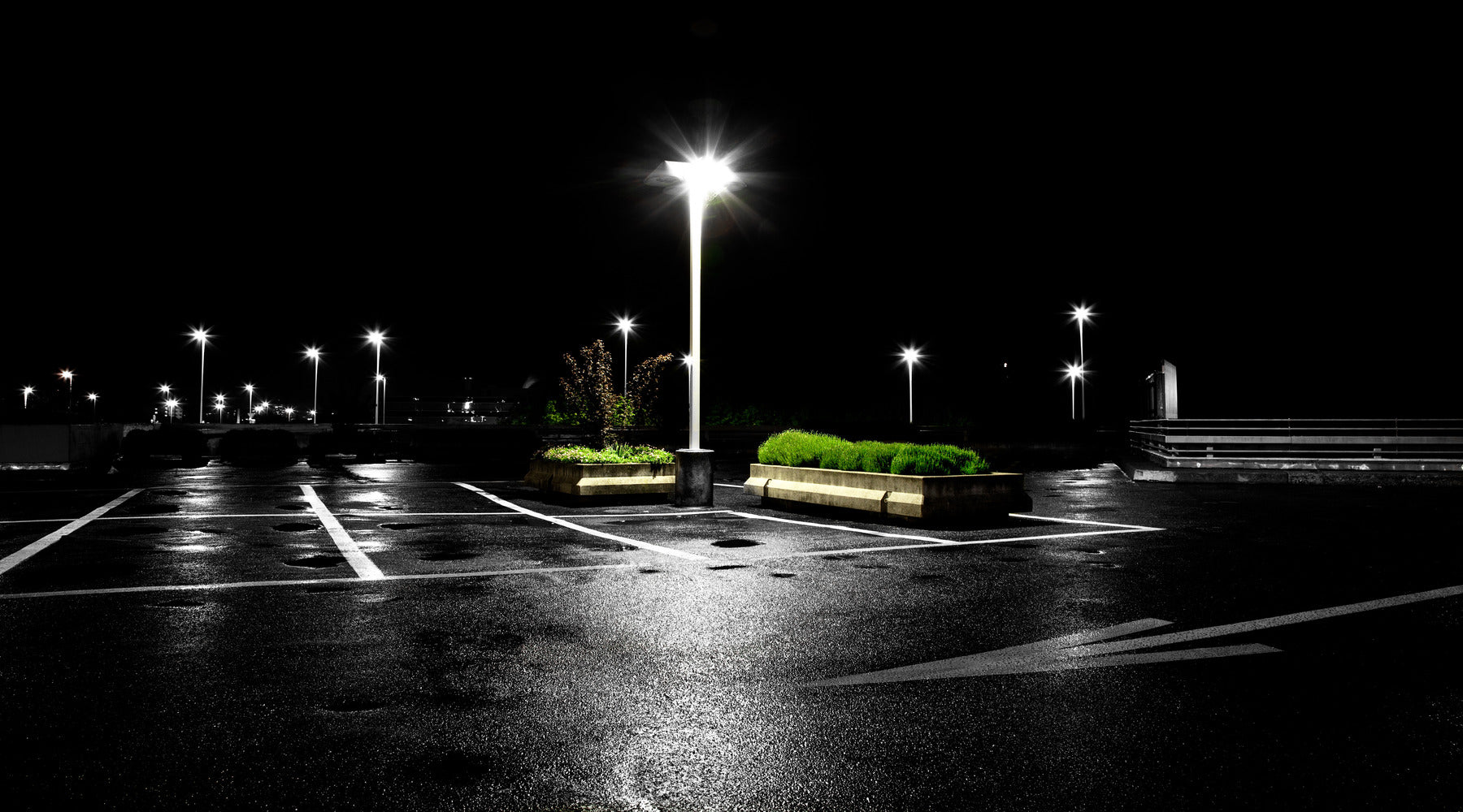 Empty parking lot shown at nighttime with parking lot lighting illuminating the entire area