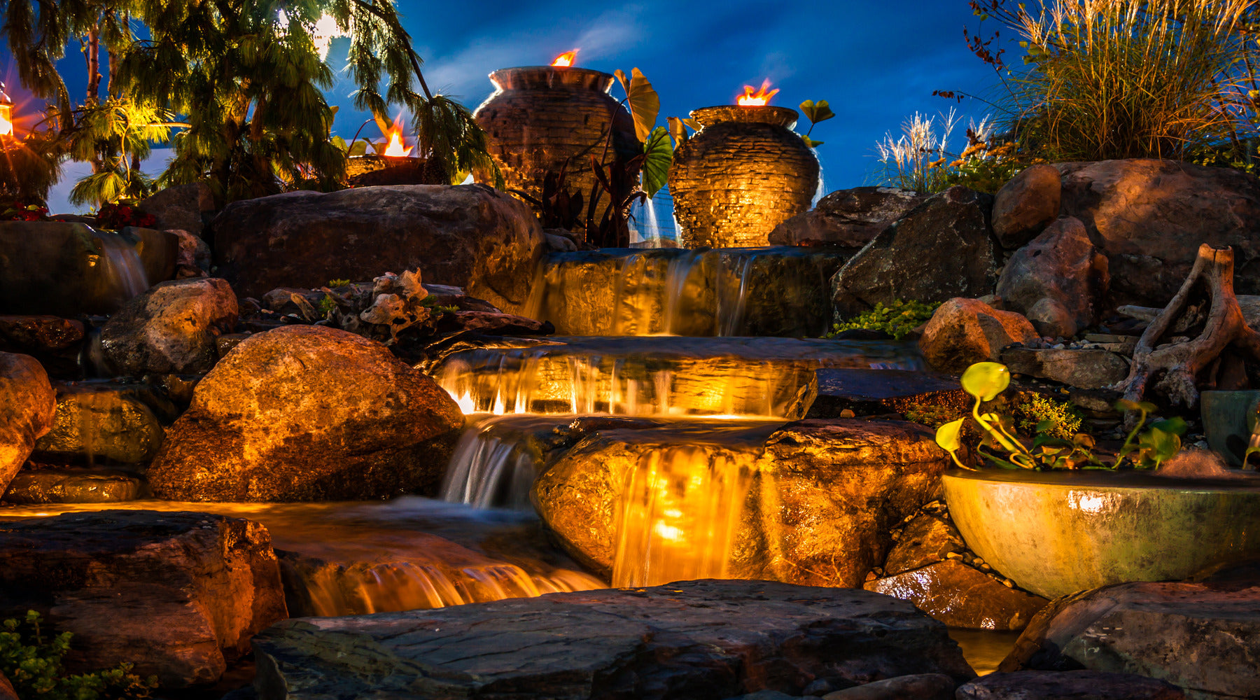 Lanscape lighting shown illuminating waterfall fountain at night