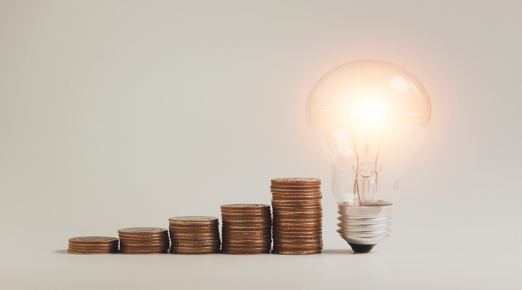 LED light bulb shown beside stacks of money coins