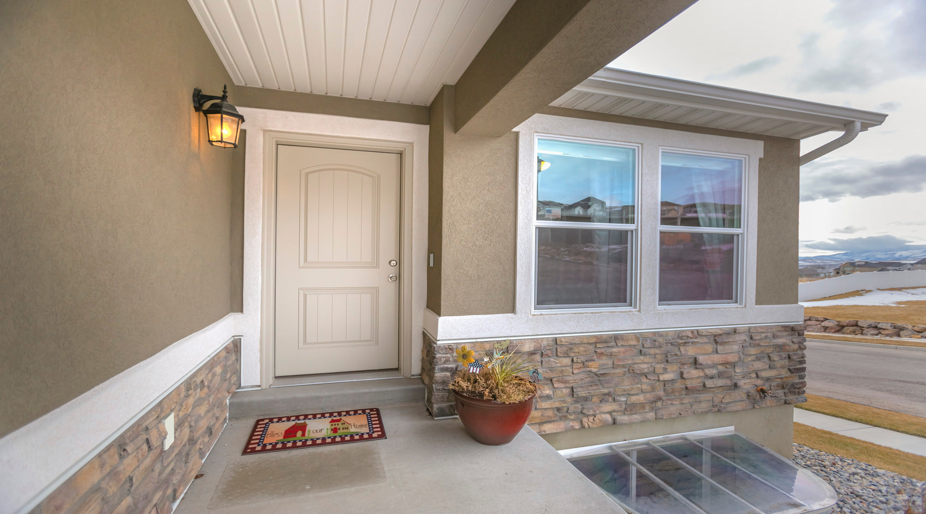 LED security light shown next to white front door with cloudy sky