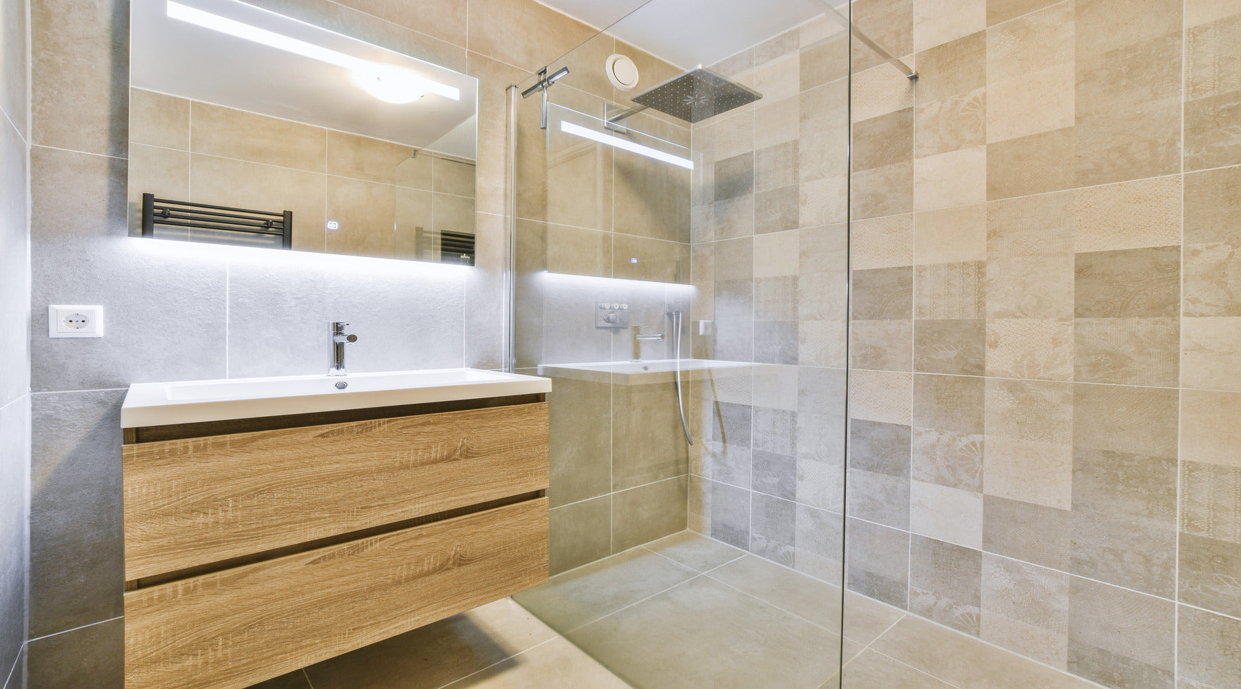 Modern bathroom with vanity being illuminated by LED tape lights installed behind glass mirror