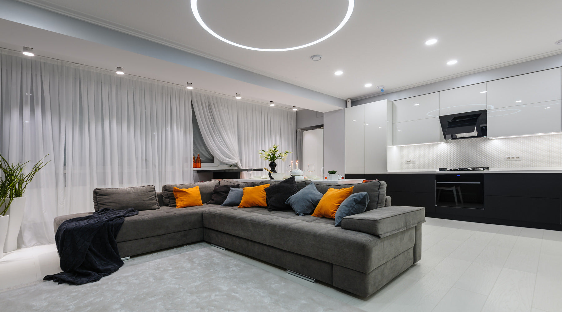 Modern white kitchen and living room shown with LED lights