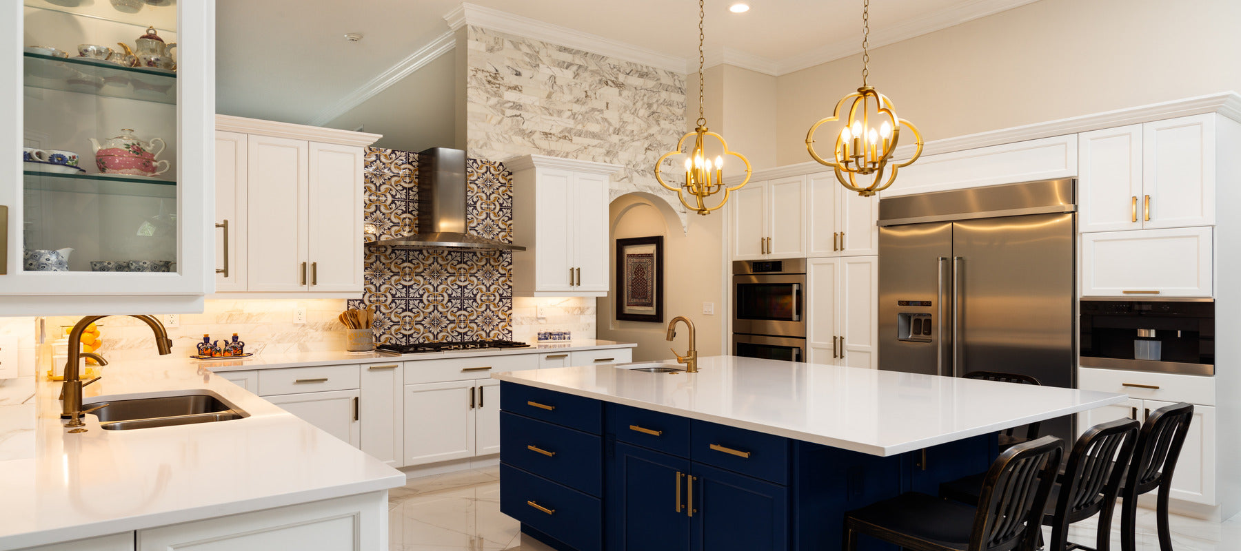 Modern white kitchen with decorative lighting hanging over island and recessed ceiling lights mounted in the ceiling