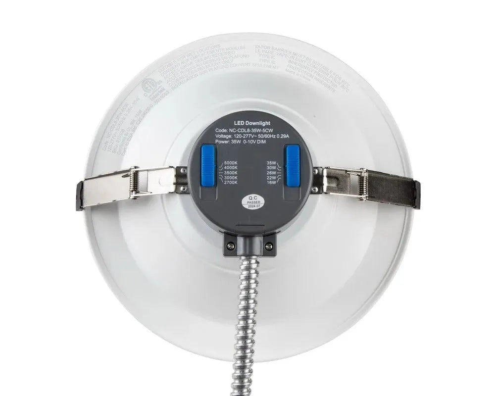 Top view of RecessEdge Series LED commercial downlight showing selectable CCT and wattage slide switches with mounting clips and flex conduit entry