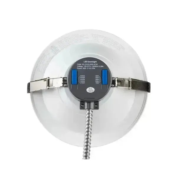 Top view of RecessEdge Series LED commercial downlight showing selectable CCT and wattage slide switches with mounting clips and flex conduit entry